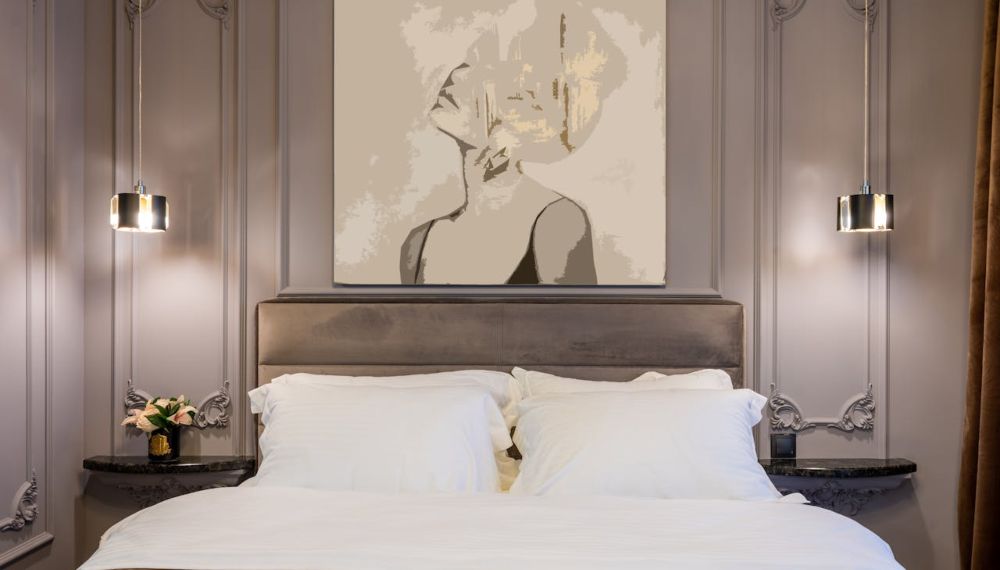 Letto appoggiato a un muro nel quale è presente un grande quadro