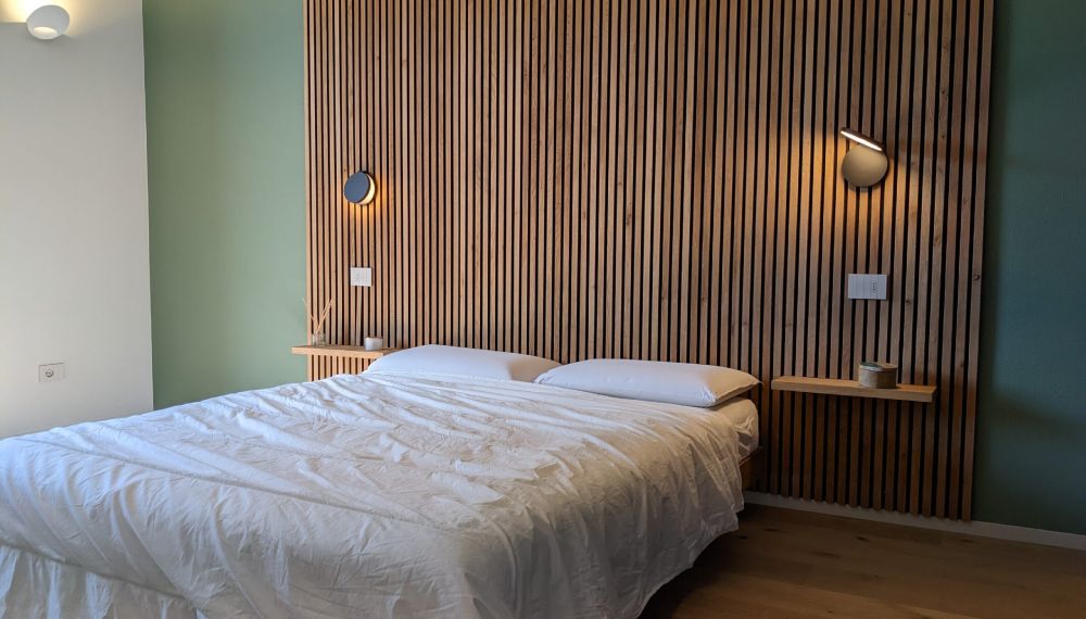 Letto con testiera in legno a cui sono appese due applique