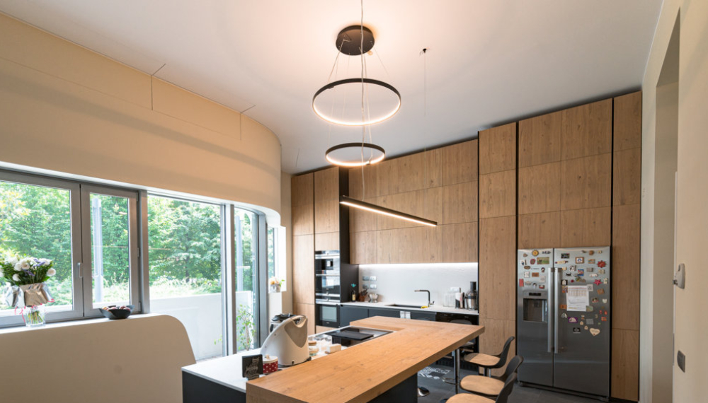 Open space moderno con illuminazione a led geometrica sospesa sulla penisola della cucina
